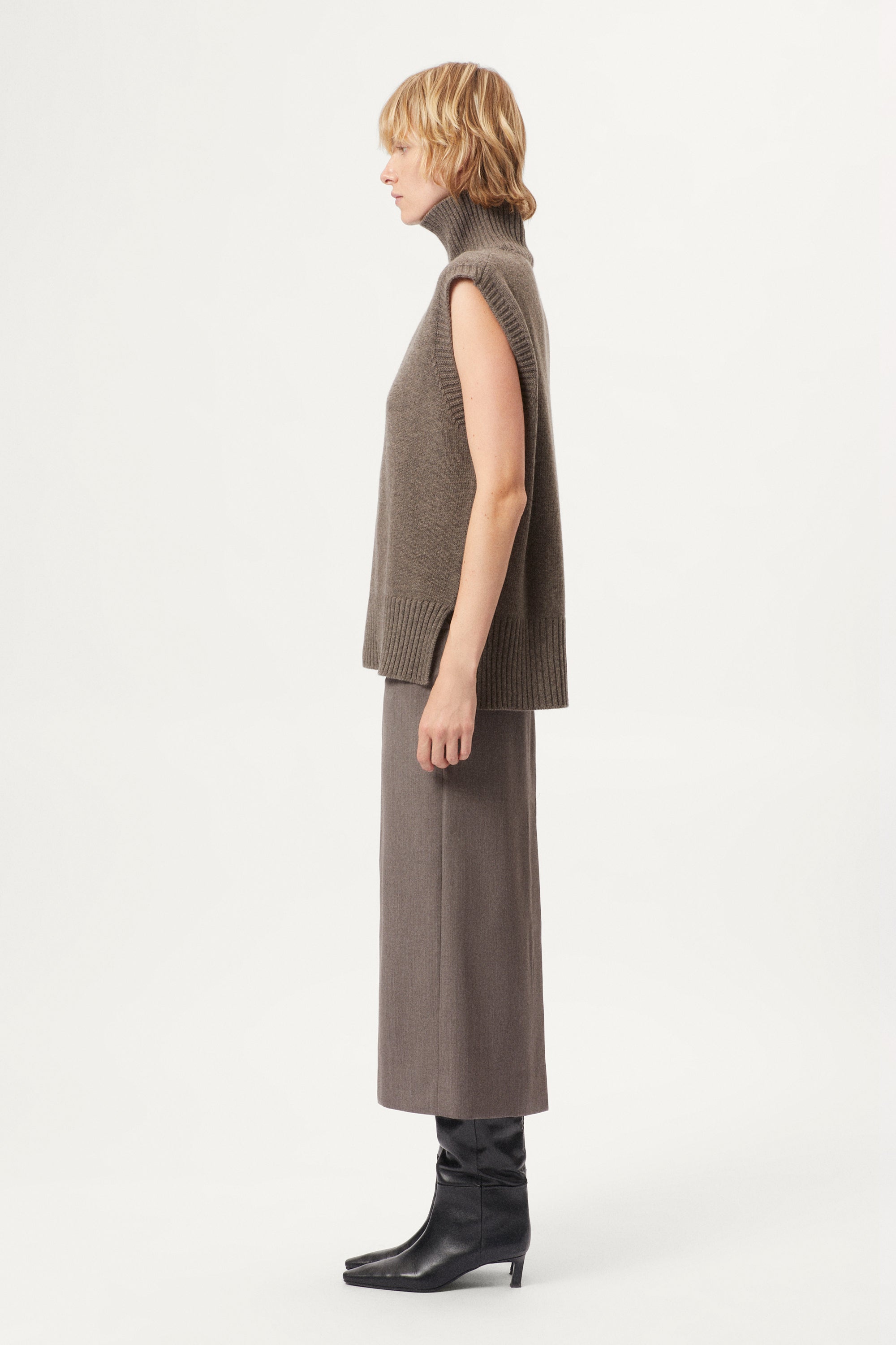 woman wearing a wool brown sleeveless high neck knitted top and skirt set on a white background