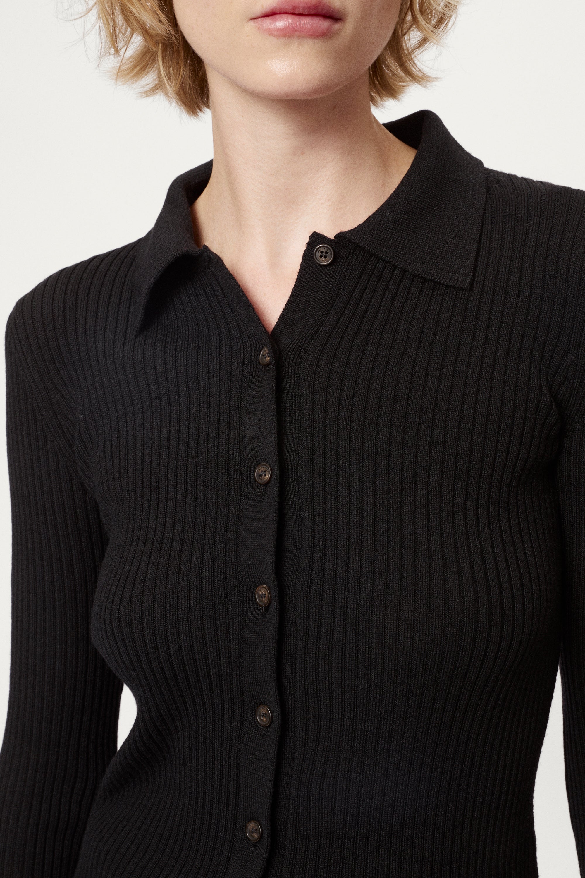 Woman wearing a black ribbed merino shirt on a white background