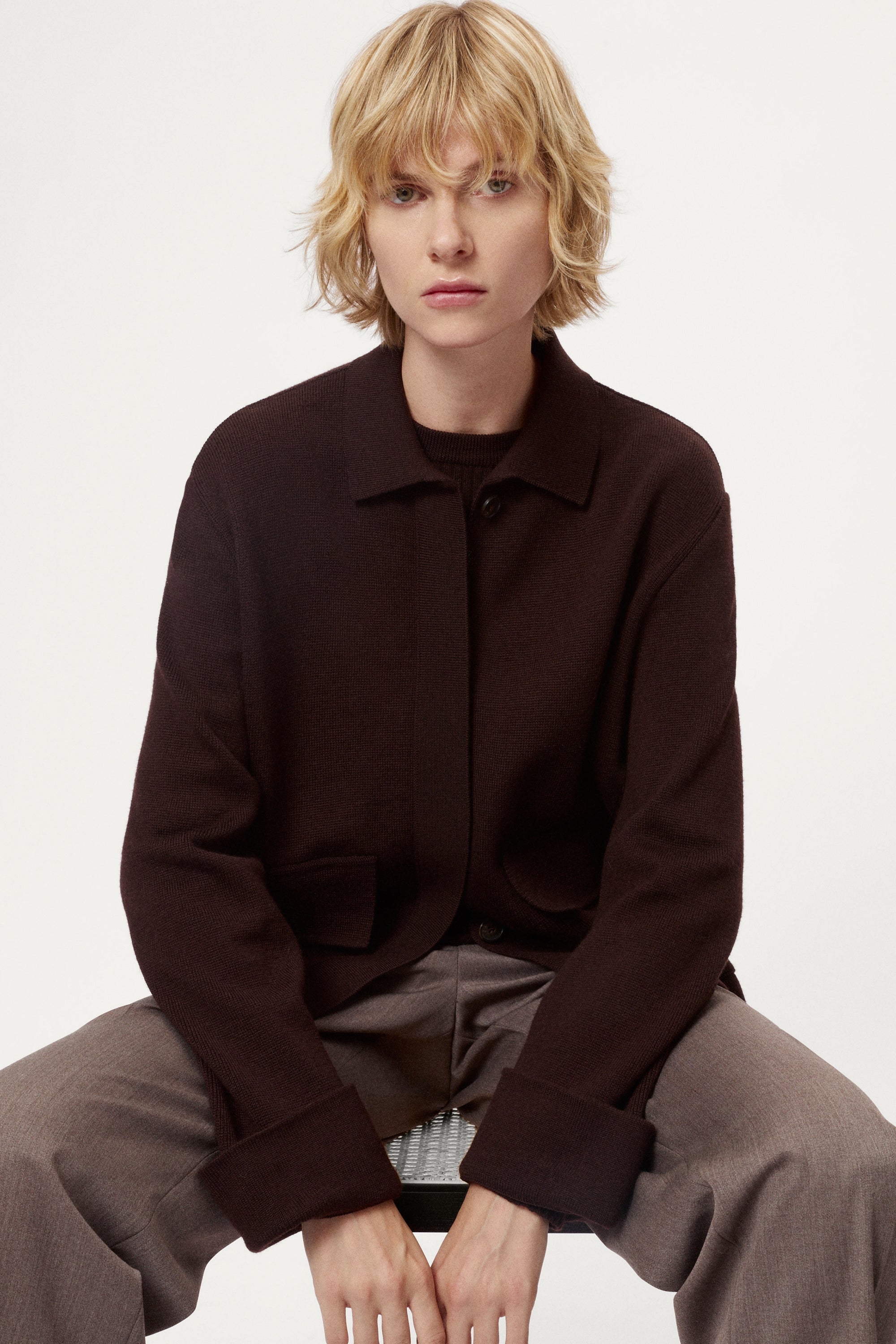 Woman wearing a dark brown jacket and pants on a white background