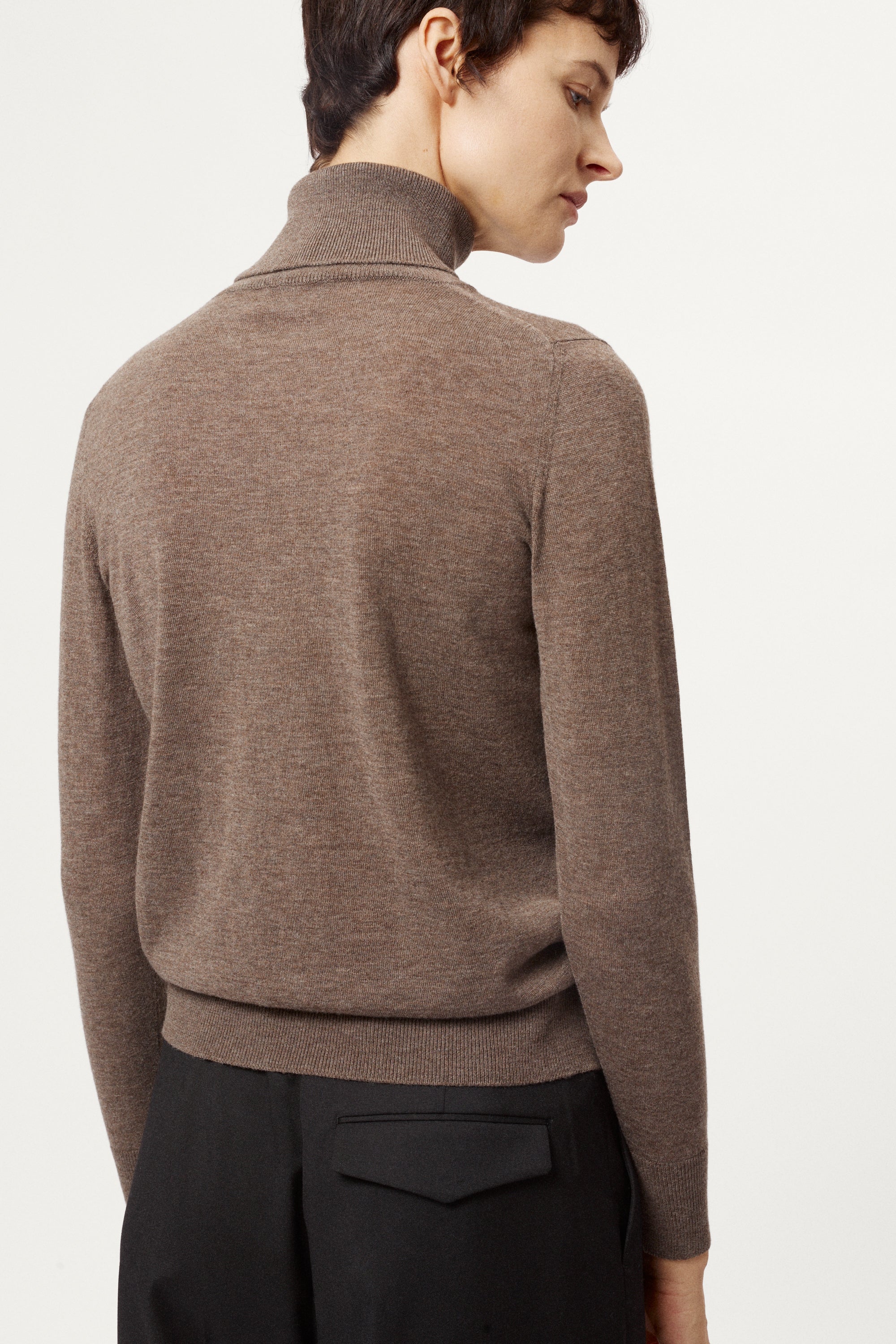 Person wearing a brown turtleneck sweater on a white background