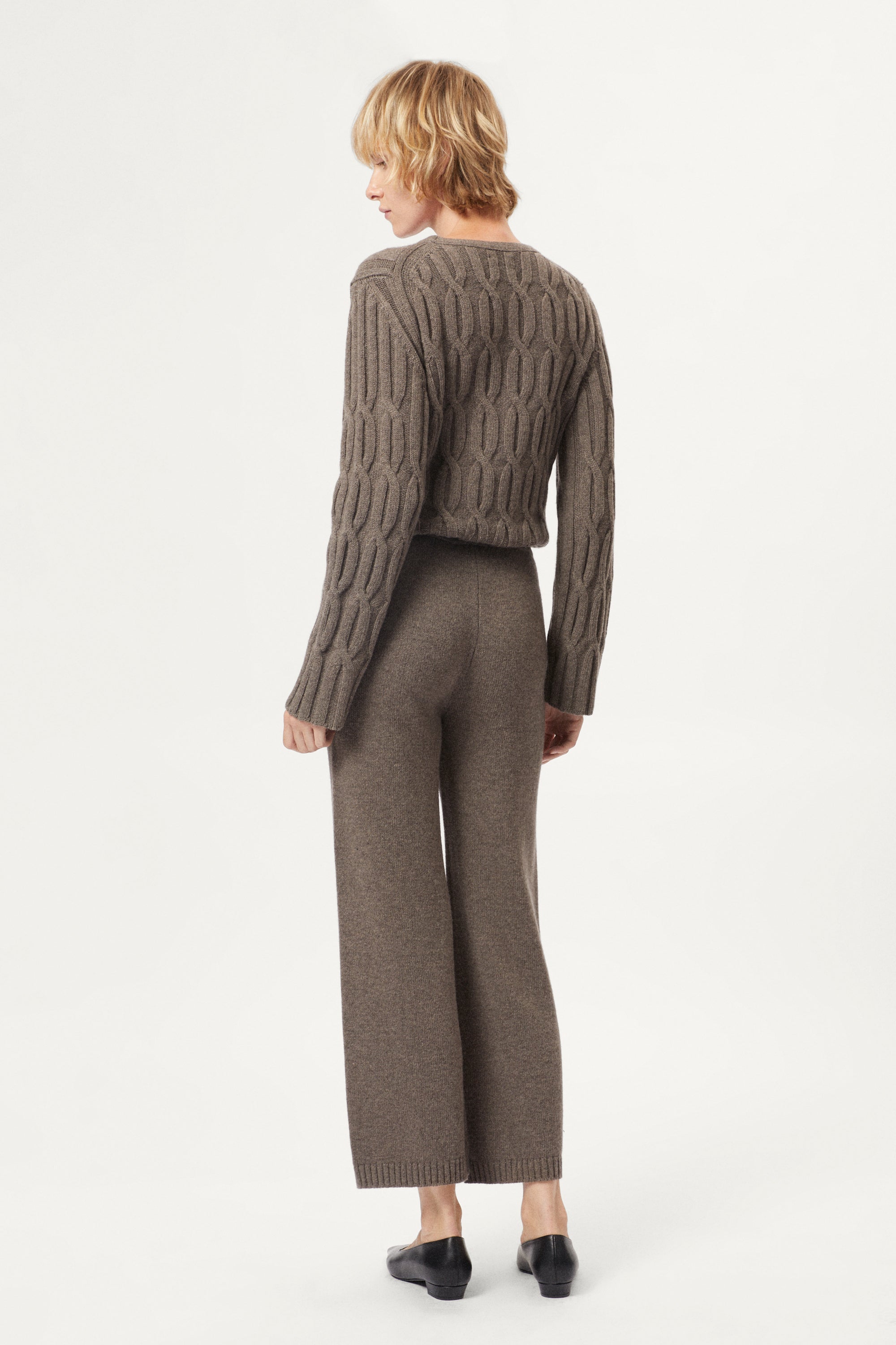 Woman wearing a brown cable knit sweater and matching taupe woolen knitted pants