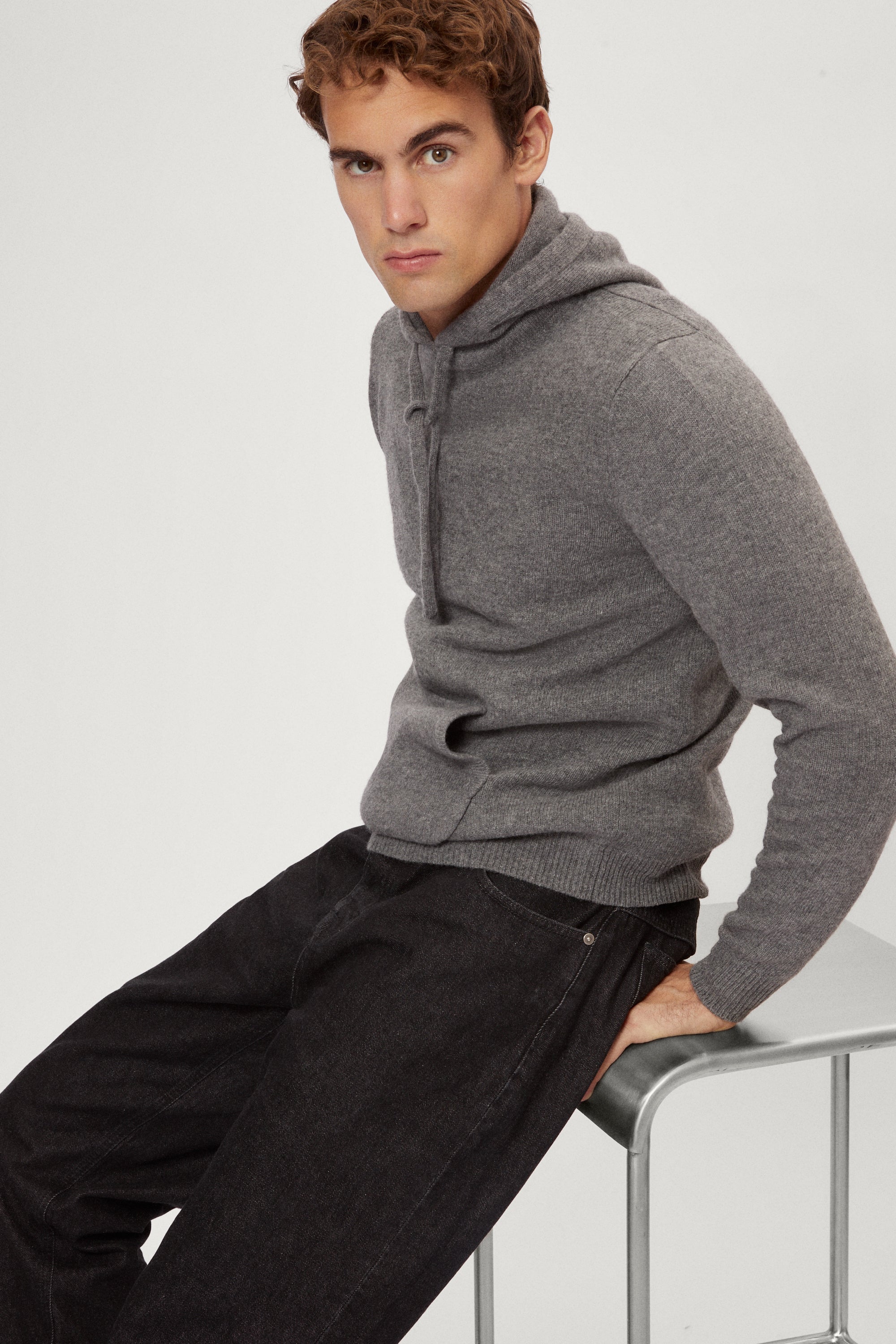 Man wearing a light gray woolen hoodie on a white background