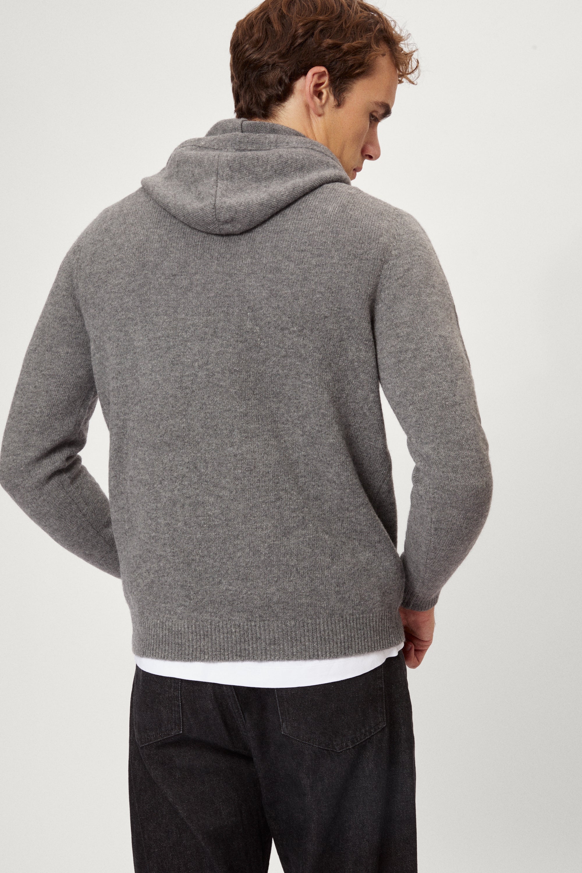 Man wearing a light gray woolen hoodie on a white background
