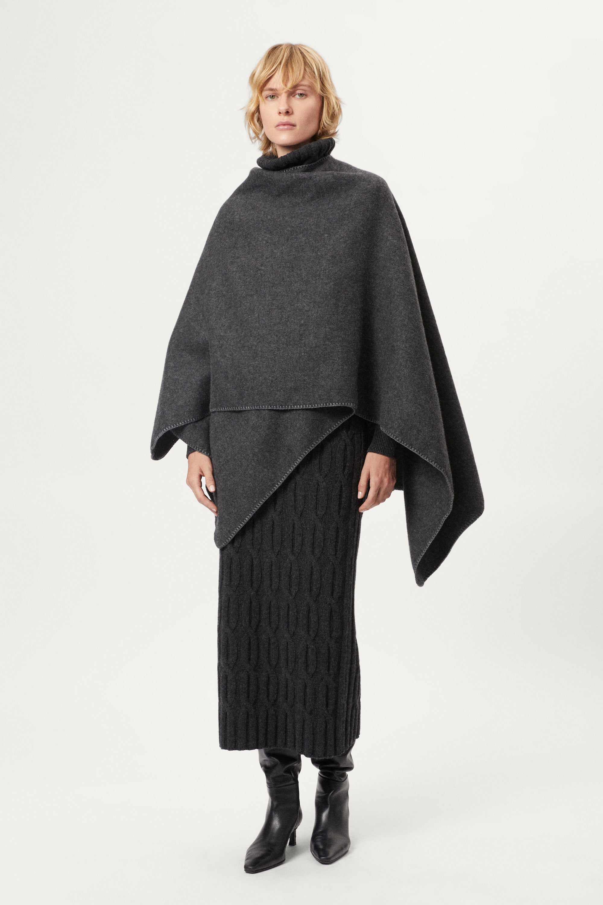 woman wearing a gray poncho over a grey outfit on a white background