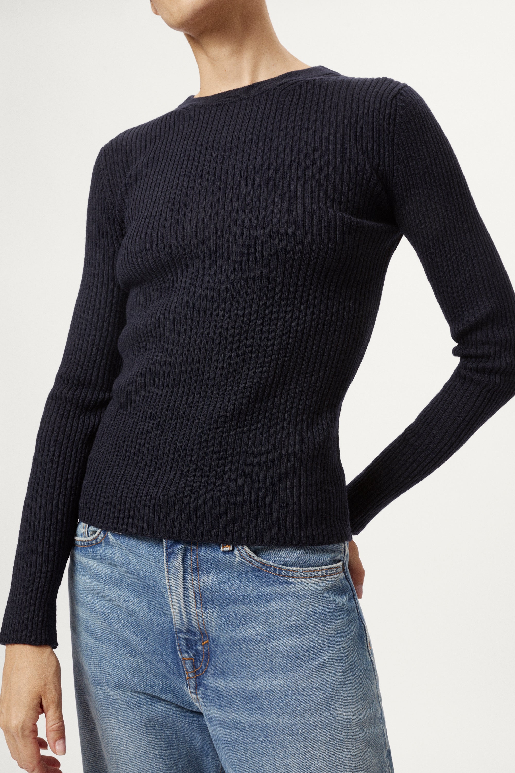 Woman wearing a blue sweater and light blue jeans on a white background